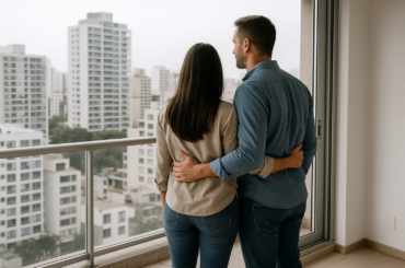 Pareja observando el crecimiento del sector inmobiliario desde el balcón de un moderno departamento en Lima con vista a edificios residenciales. Ventas del sector inmobiliario en Perú crecerán con fuerza en 2026