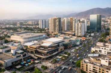 Vista aérea de una zona urbana moderna en Lima con edificios residenciales, centro comercial y avenidas con alto flujo vehicular, reflejando el crecimiento inmobiliario y comercial de la ciudad.